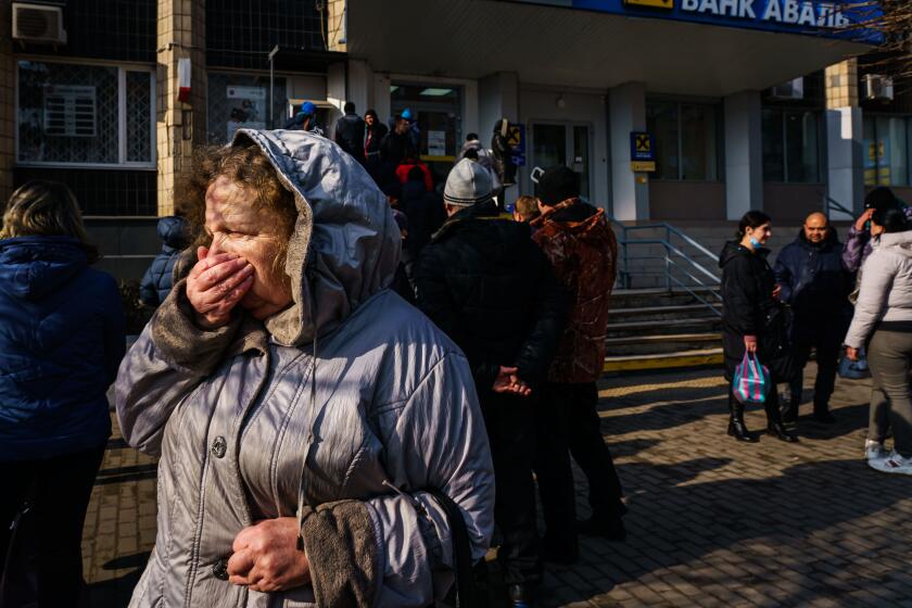 SLOVYANSK, UKRAINE -- FEBRUARY 24, 2022: A woman walks away from a line for the ATM that is growing as people try to obtain cash as news of Russia invading Ukraine continues to dominate the headlines, in Slovyansk, Ukraine, Thursday, Feb. 24, 2022. (MARCUS YAM / LOS ANGELES TIMES)