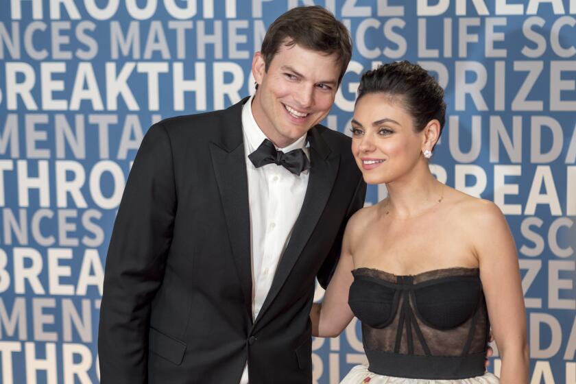 A husband and wife in formalwear pose for a photo