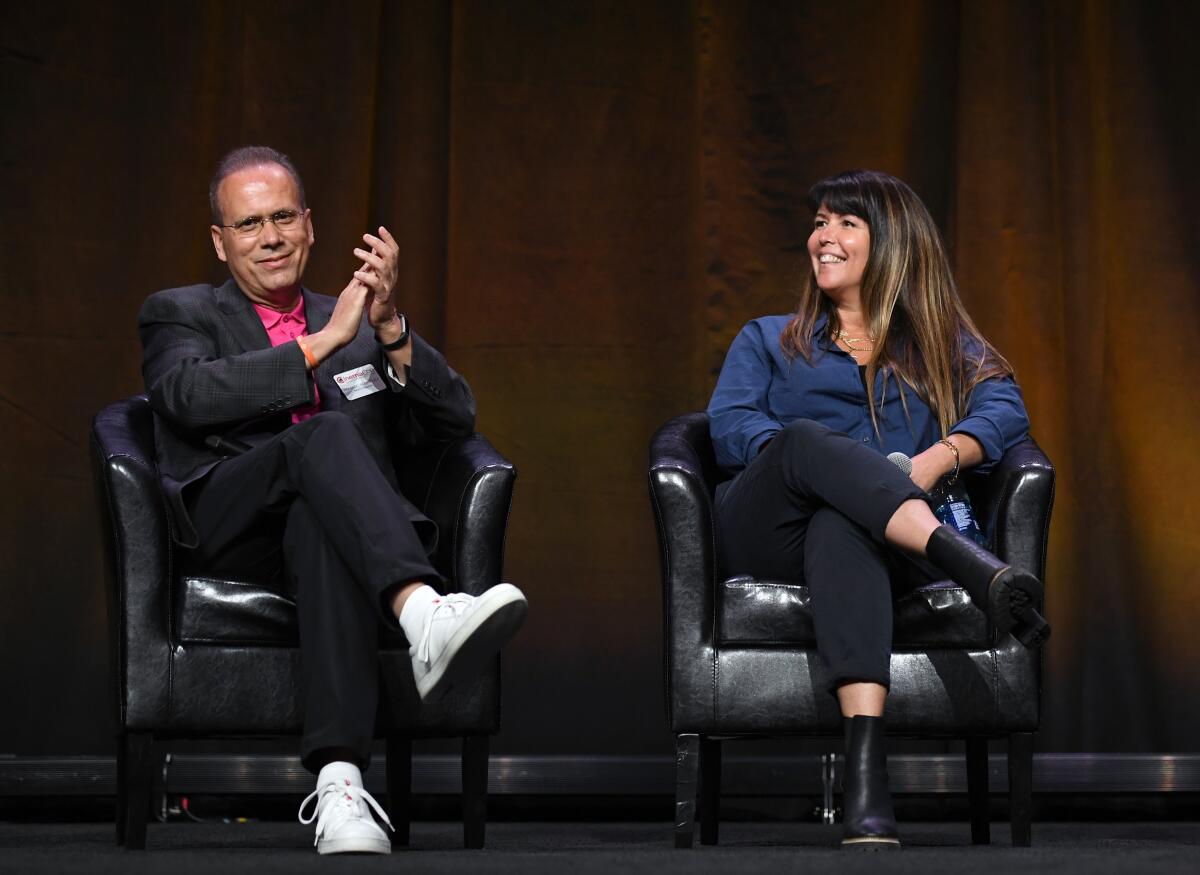 A man and woman in chairs on a stage