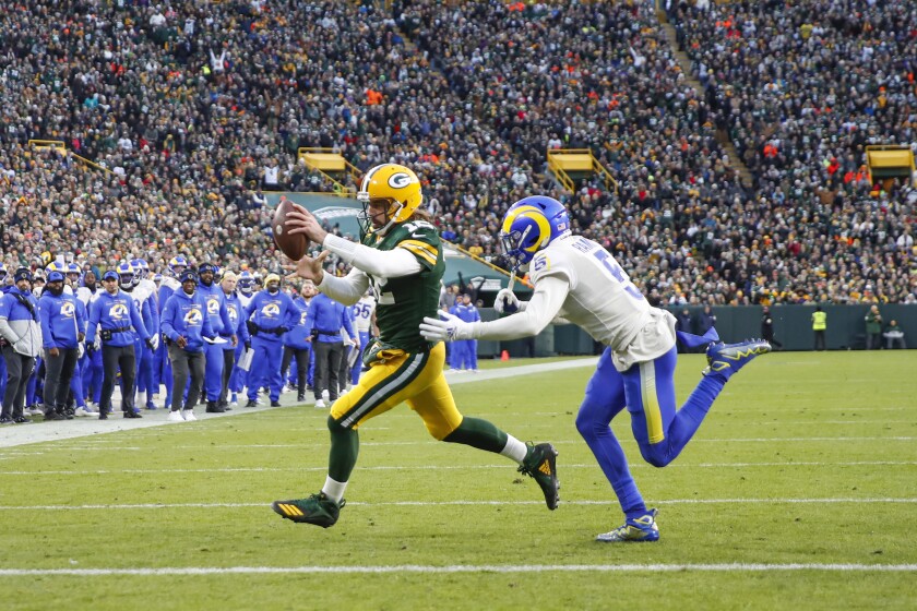 Green Bay Packers quarterback Aaron Rodgers runs past Rams cornerback Jalen Ramsey for a touchdown Sunday at Lambeau Field.