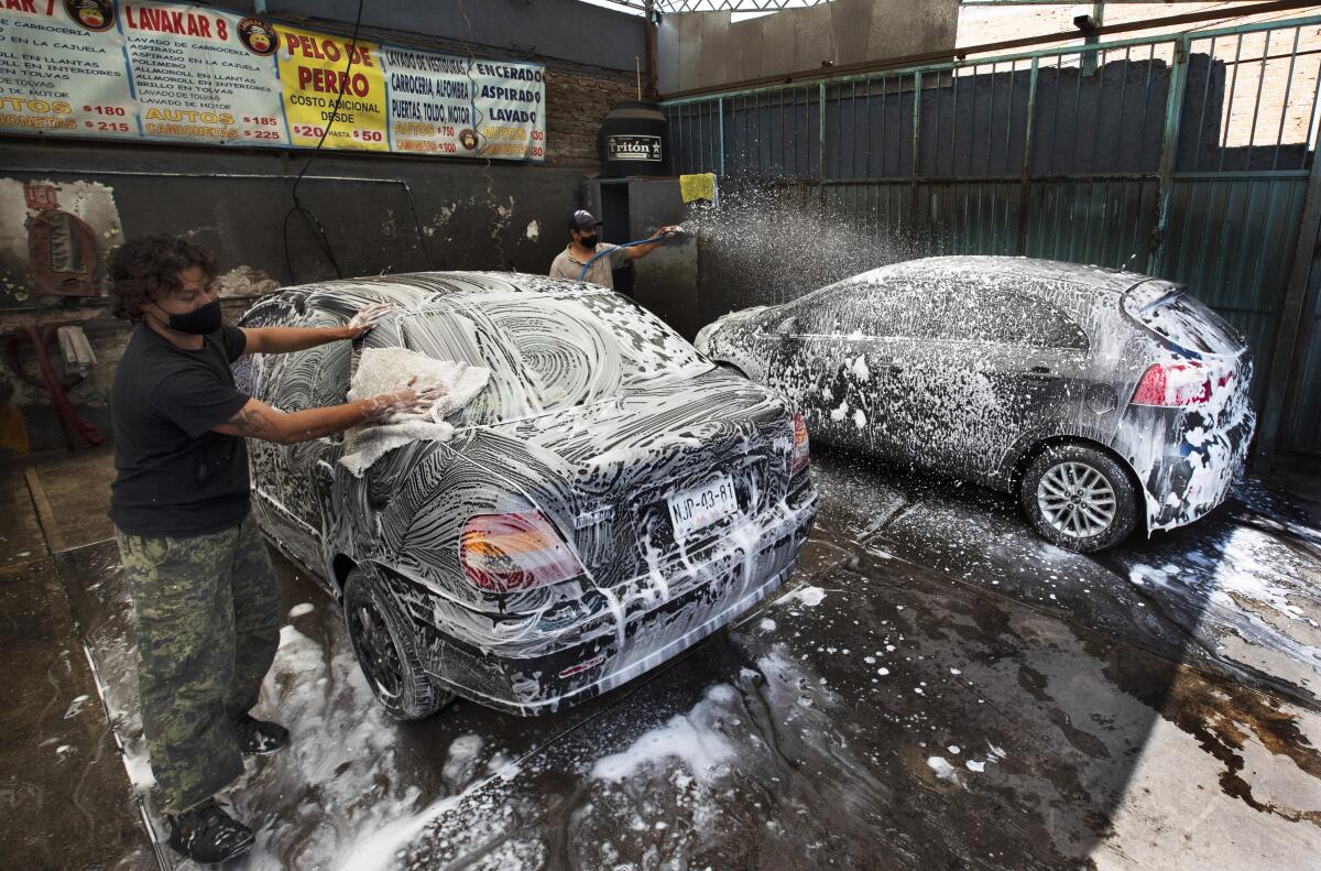 Óscar Aguilera y Juan Martínez lavan automóviles en el autolavado Lavakar, en la Ciudad de México.