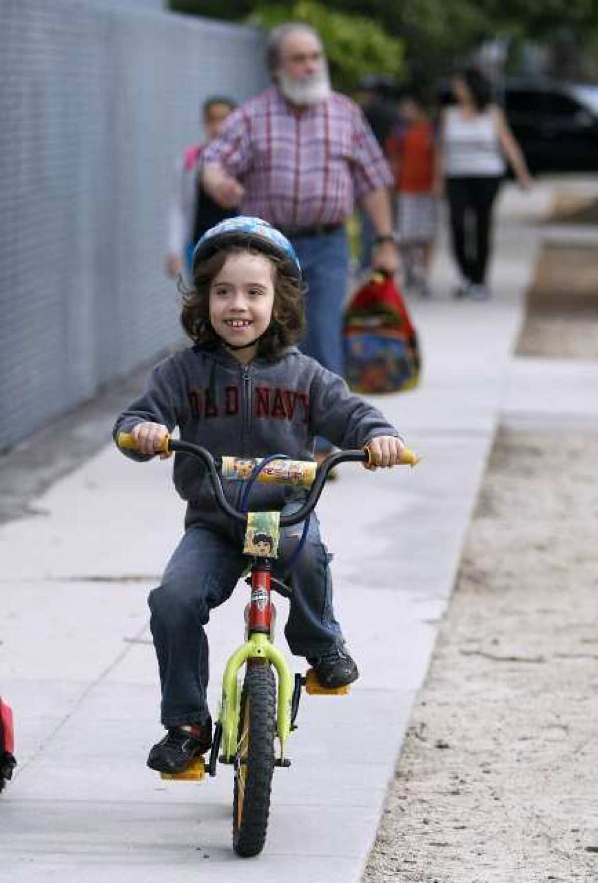 R.D. White Elementary School 1st grader Rafael Bodeant, 7, arrives to school on his bike, with his father Rafael Bodeant behind him, on Bike to School Day at the Glendale school on Wednesday, May 8, 2013. About 25 children rode their bikes to school from various locations.