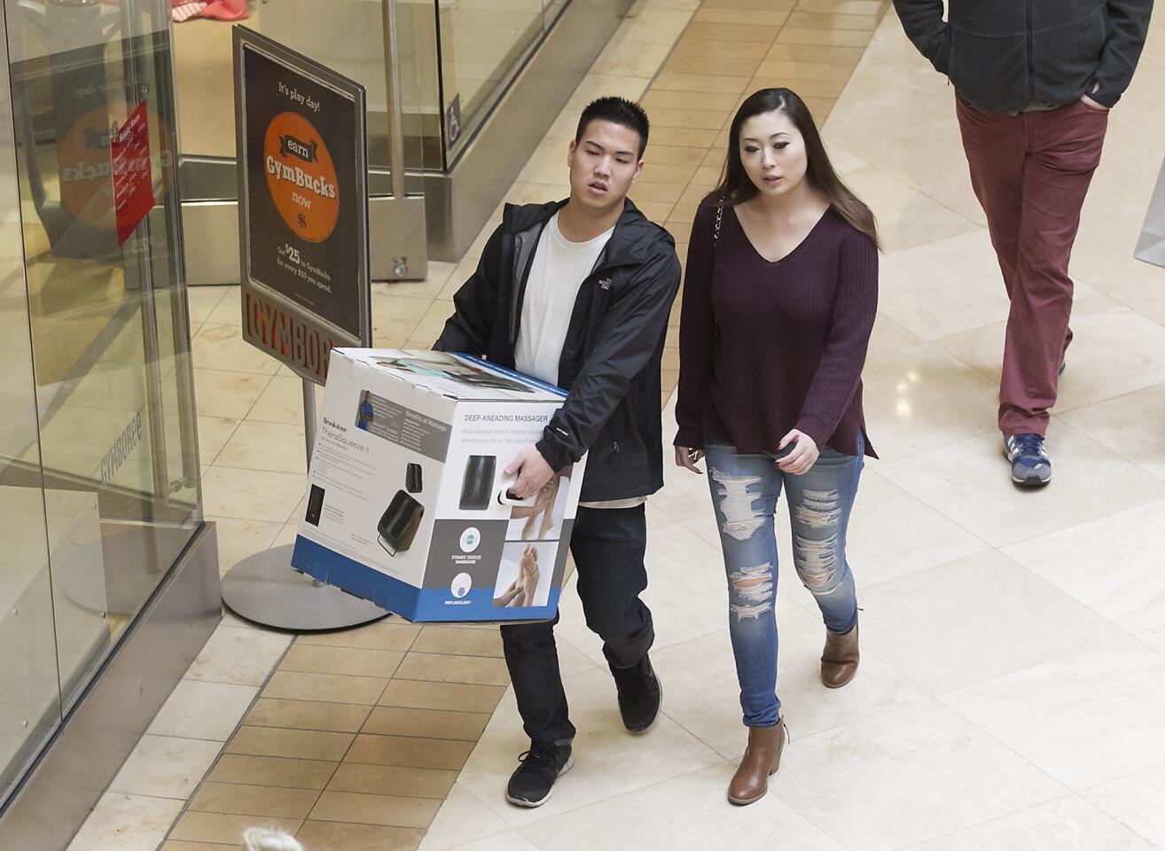 A shopper carries a foot massager bought as a gift at Costa Mesa’s South Coast Plaza on Friday, two days before Christmas.