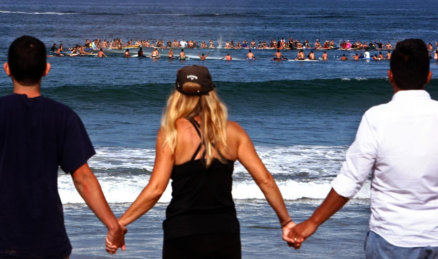 Close to 300 people, on surfboards and on land, participate in a paddle out and memorial for Mason Zisette at Manhattan Beach.