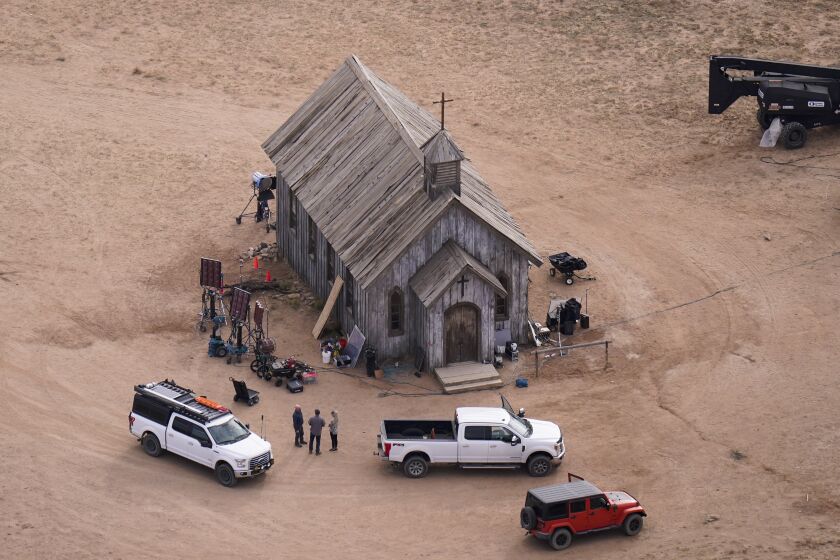 An aerial shot of an old, wooden church building surrounded by people, equipment and trucks
