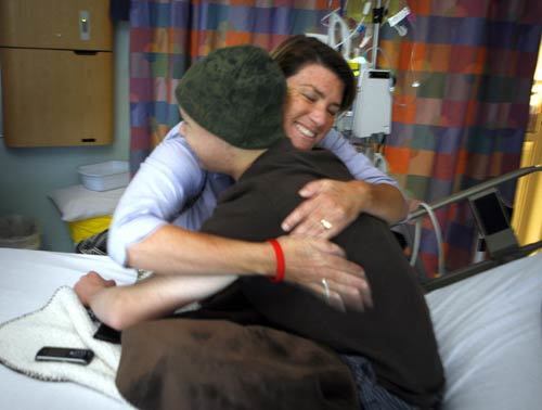 With chemotherapy and other medications pumping away at his bedside at Children's Hospital of Orange County in Orange, Chase Crawford-Quickel gets a hug from one of his teachers at Aliso Niguel High School, Cindy Wright, after receiving his diploma.