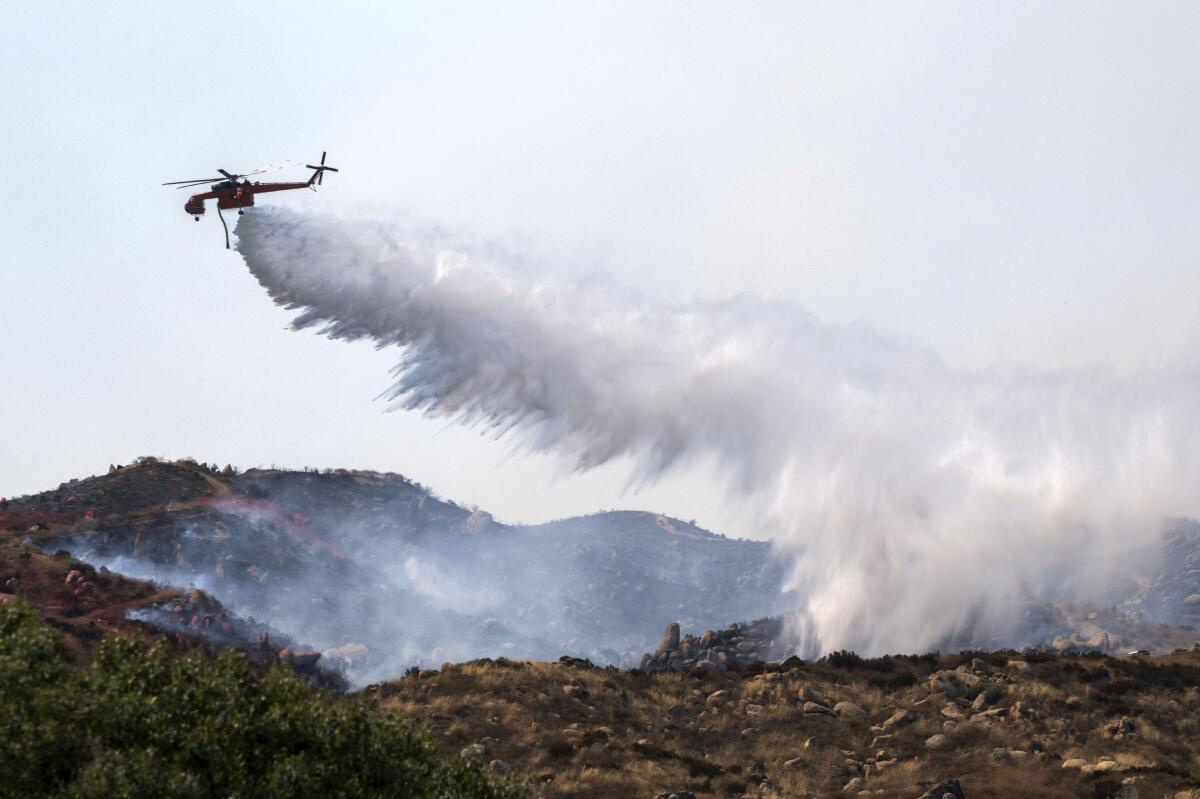 Un helicóptero trata de apagar un incendio en Reche Canyon cerca de Moreno Valley, California