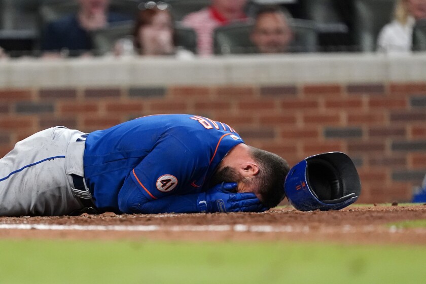 New York Mets' Kevin Pillar lies on the ground after being hit in the face with a pitch from Atlanta Braves pitcher Jacob Webb in the seventh inning of a baseball game Monday, May 17, 2021, in Atlanta. (AP Photo/John Bazemore)