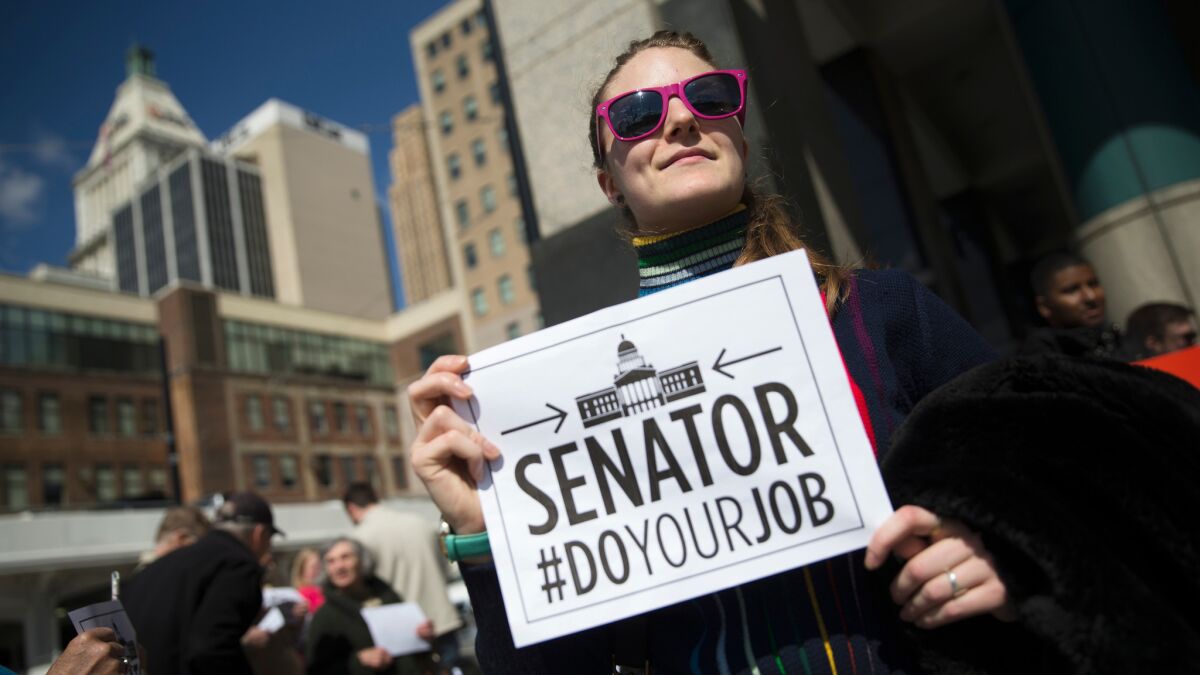 A picketer stands outside the office of Sen. Rob Portman, R-Ohio, in Cincinnati on March 21. The protest was part of a group of rallies around the country targeting Republican senators who opposed confirmation hearings for the president's Supreme Court nominee Merrick Garland.