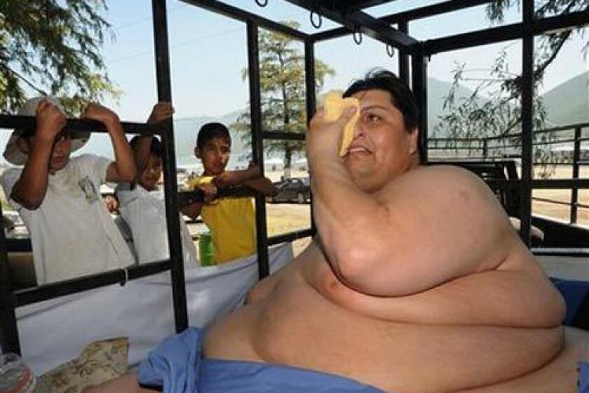 Manuel Uribe, better known as "Meme" who weights around 310 kilograms (700 pounds), wipes his face inside a trailer holding his specially designed bed on a trip to a lake while children look at him in Monterrey, northern Mexico, yesterday. Uribe, 43, who once weighed half a ton, has been largely confined to his home for the last six years.