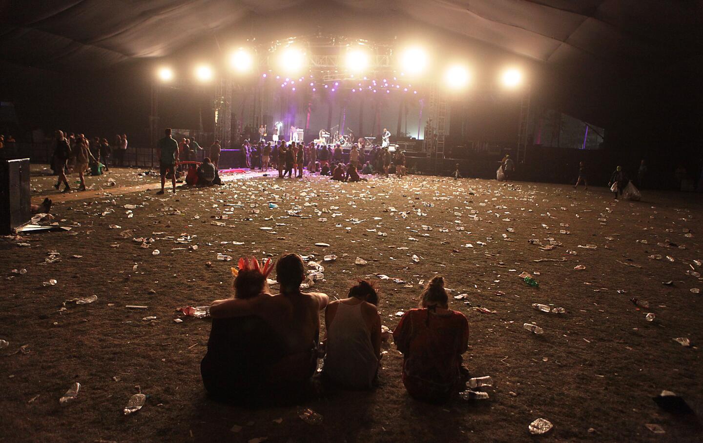 Fans sit on a trash-strewn lawn in front of the Gobi stage between shows on the second day of the Coachella Valley Music and Arts Festival in Indio.
