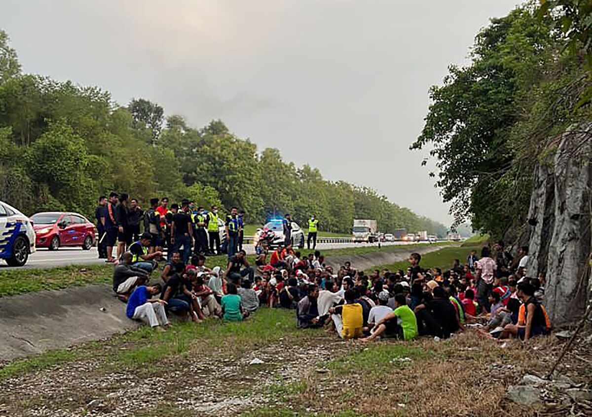 In this photo released by the Malaysia Royal Police, police detain Rohingya refugees who had escaped from the Sungai Bakap Temporary Immigration Depot, Penang, Malaysia, Wednesday, April 20, 2022. More than 500 Rohingya refugees escaped from detention in Malaysia following a protest and most have been rearrested. (Malaysia Royal Police via AP)