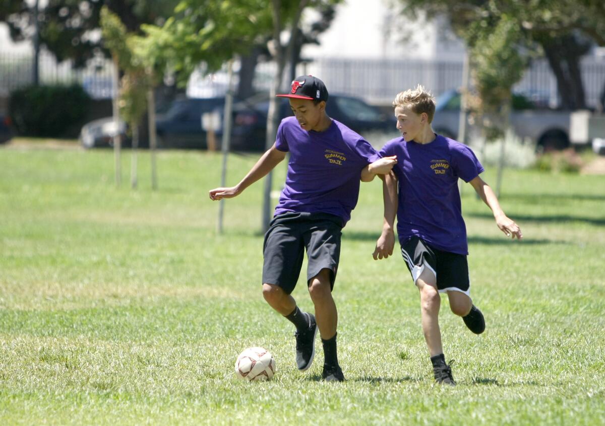 From left, Marcus Halm, 13, and Wilson Harting, 12, play soccer at the annual Summer Daze Camp at Johnny Carson Park in Burbank on Thursday, Aug. 11, 2016.