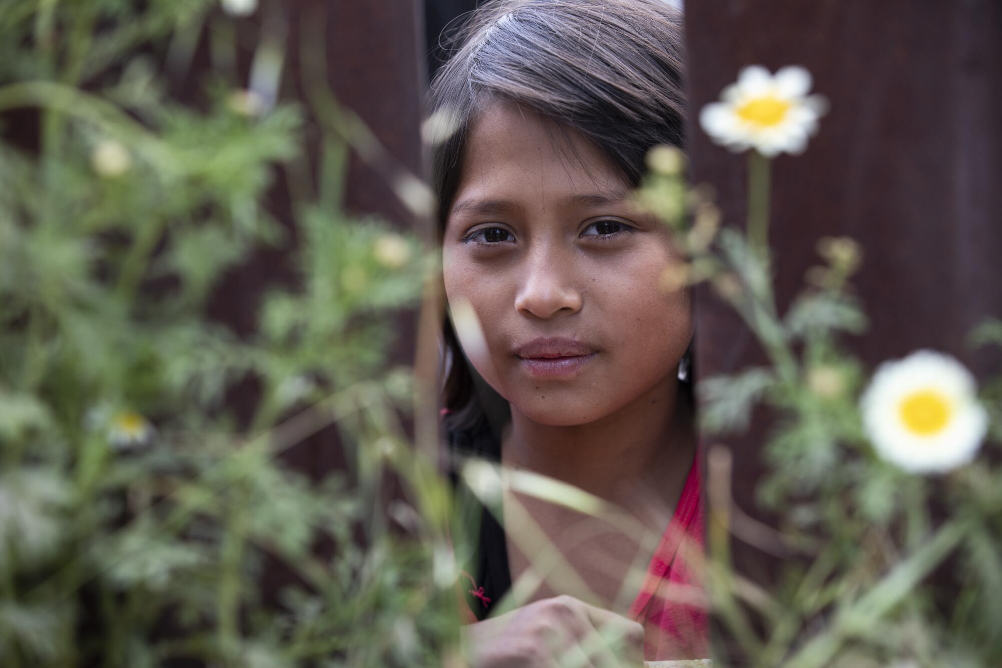 A 10-year-old girl stands on the other side of the border wall