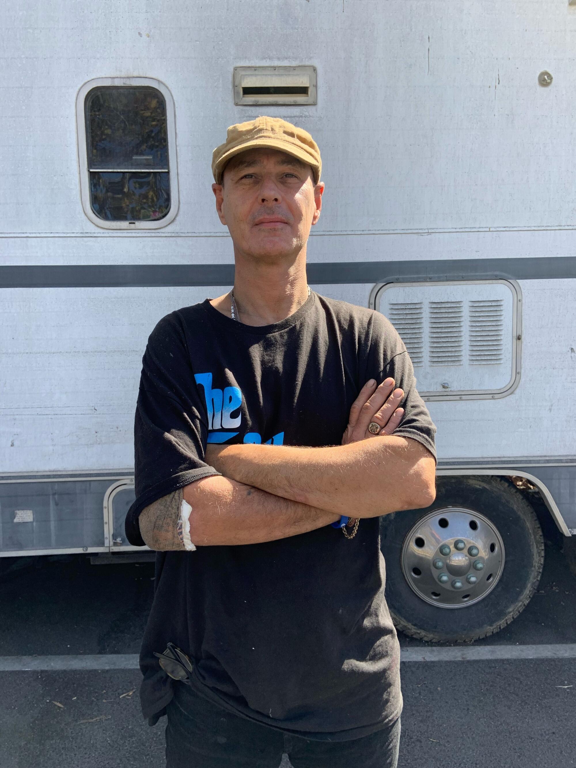 A man with his arms crossed in front of a bus