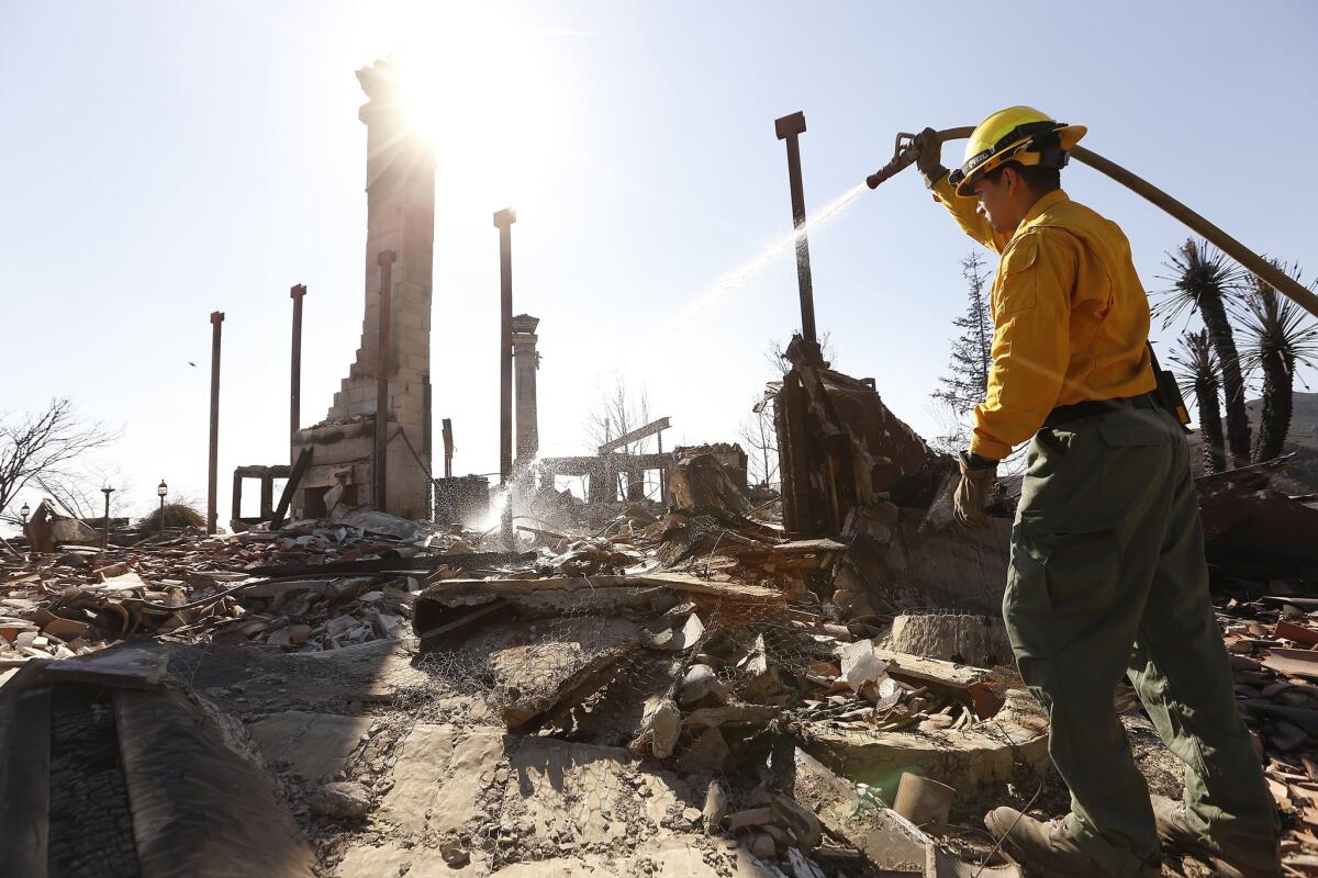 Eloy, Ariz., firefighter Adan Rodriguez puts water on a hot spot at a home on Mulholland Drive in Malibu.