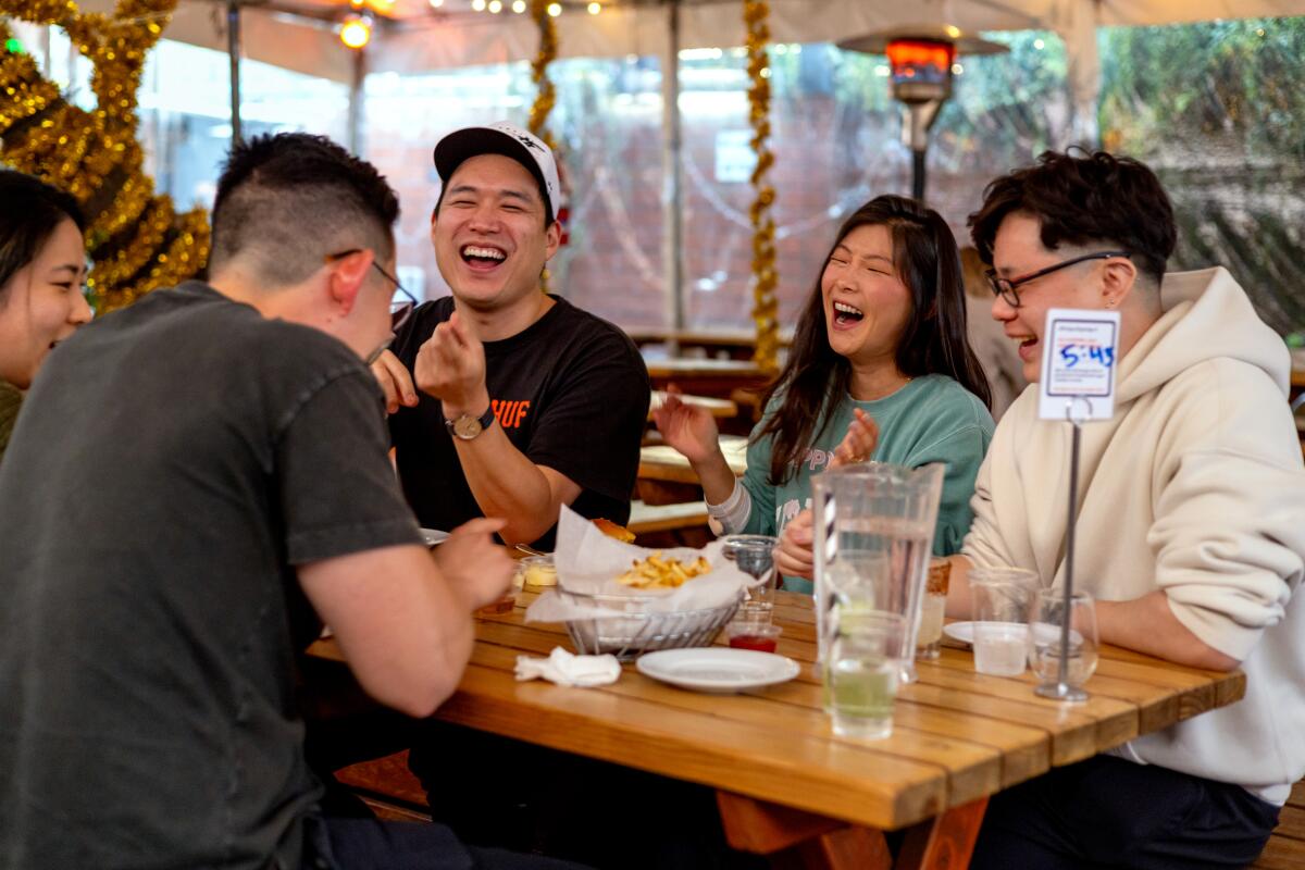 A group of diners laugh over drinks and food