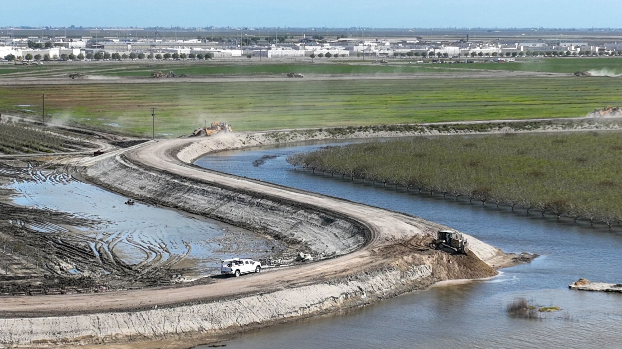  Earth moving machinery toils atop a dirt levee.