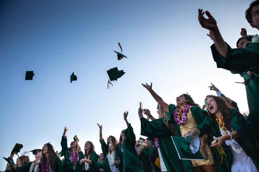 MANHATTAN BEACH, CA - JUNE 11: Graduates from Mira Costa High School in Manhattan Beach, CA, celebrate by tossing their caps in the air, on the beach next to the Manhattan Beach Pier, after their drive-through ceremony and a walk along the Strand path from Hermosa Beach Pier, on Thursday, June 11, 2020. (Jay L. Clendenin / Los Angeles Times)