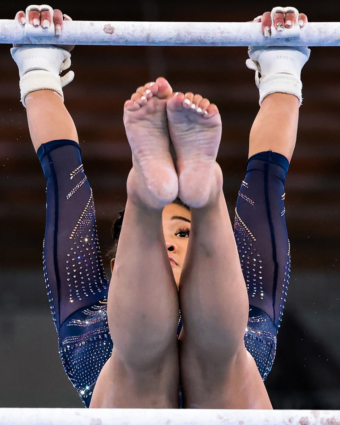 Sunisa Lee lifts her legs as she hangs from a bar.