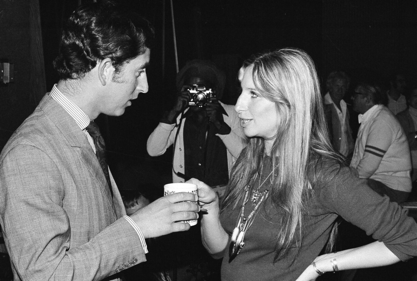 Barbra Streisand offers a cup of coffee to Prince Charles as they chat on a set at Warner Bros. studio in Los Angeles on March 19, 1974. The Prince is visiting Southern California while his ship is docked in San Diego.