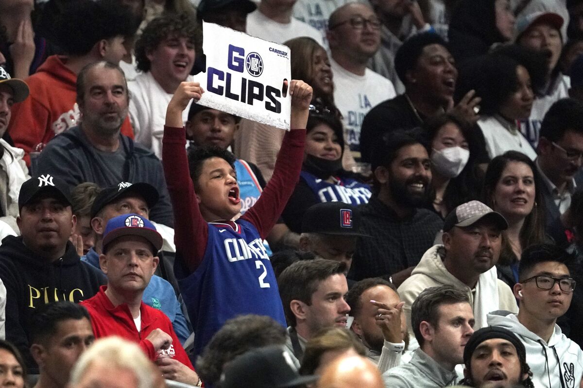 A fan cheers for the Clippers and hold a sign that reads "Go Clips!" during a game at Crypto.com Arena.