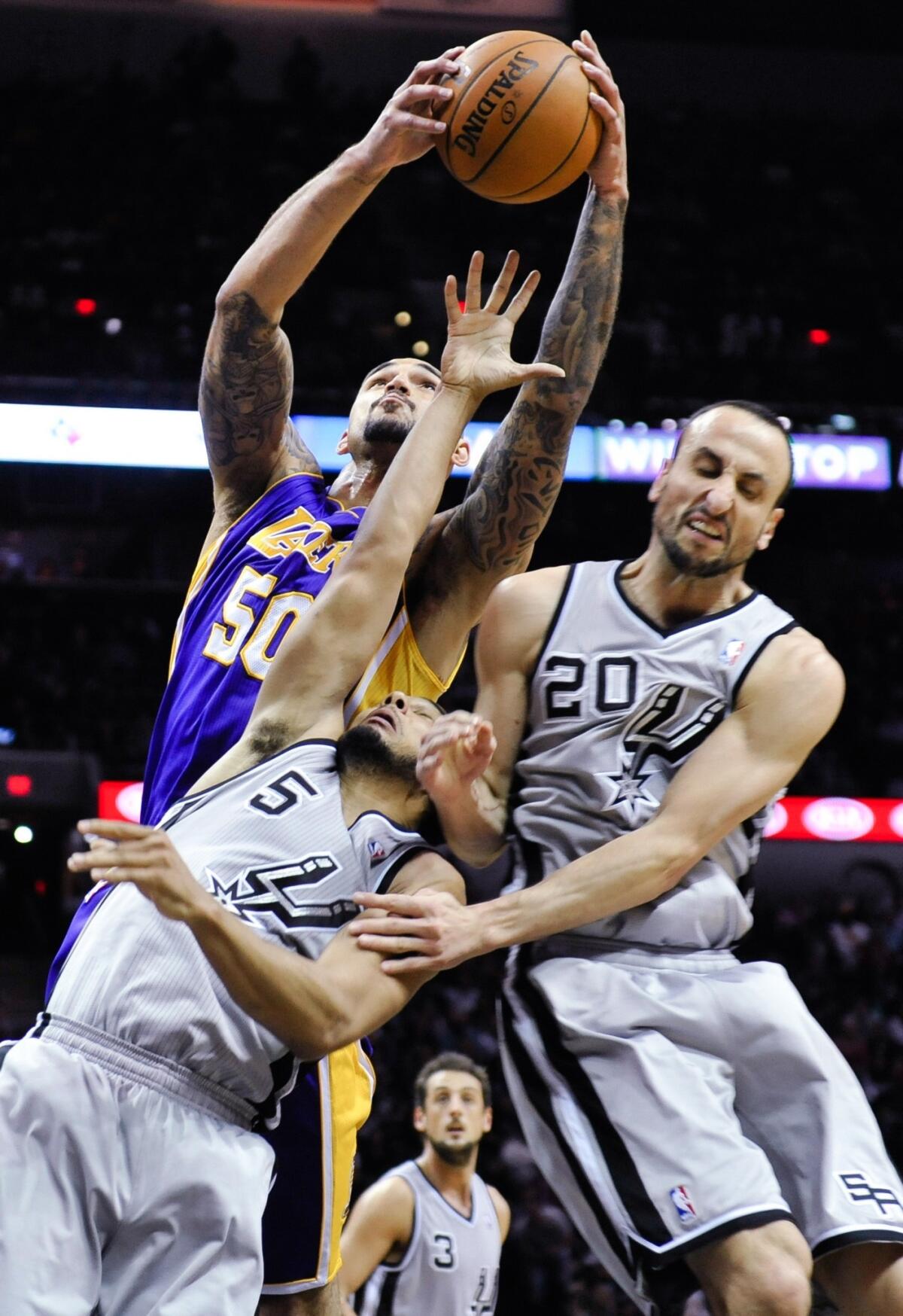 Lakers center Robert Sacre goes above Spurs guard Cory Joseph (5) and Manu Ginobili for a rebound in the second half.