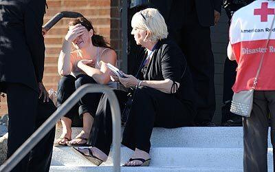 A distraught woman is counseled in front of Gateway High School in Aurora, Colo.