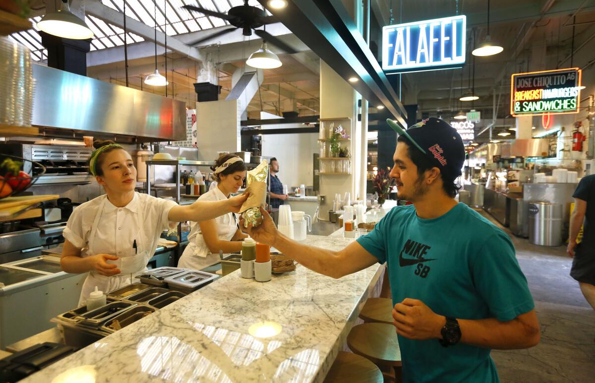 Chef Sarah Hymanson, left, hands a falafel sandwich to customer Ryan Badaraco at Kismet Falafel, previously Madcapra.