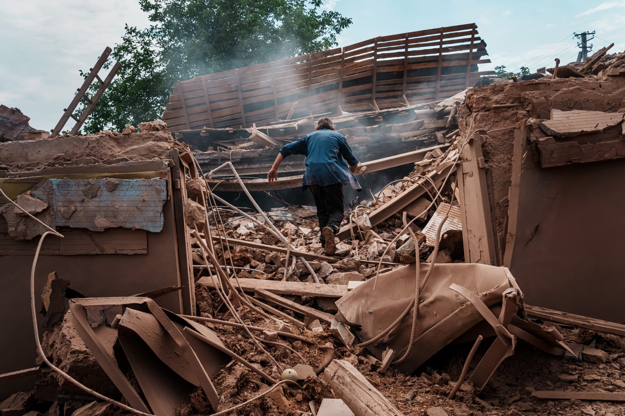 A person seen from behind walks amid a mountain of brown rubble 