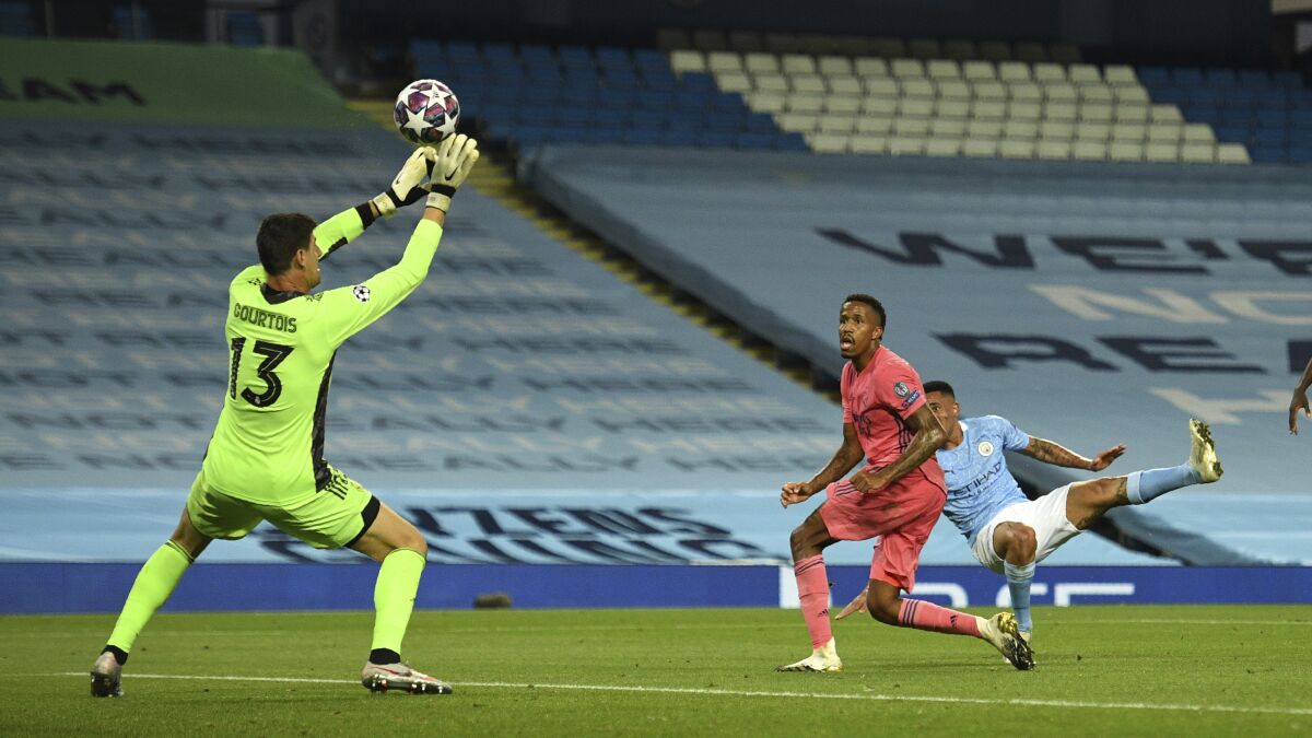 Real Madrid's goalkeeper Thibaut Courtois saves a shot by Manchester City's Gabriel Jesus during the Champions League, round of 16, second leg soccer match between Manchester City and Real Madrid at the Etihad Stadium in Manchester, England, Friday, Aug. 7, 2020. (Oli Scarff/Pool Photo via AP)