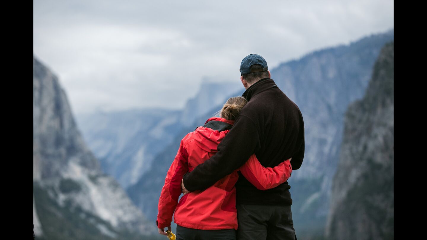 A couple embrace while looking down the Yosemite Valley.
