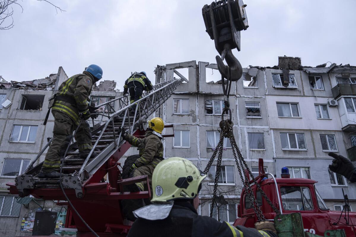 Workers climbing up to clear rubble from top of building damaged by Russian rocket