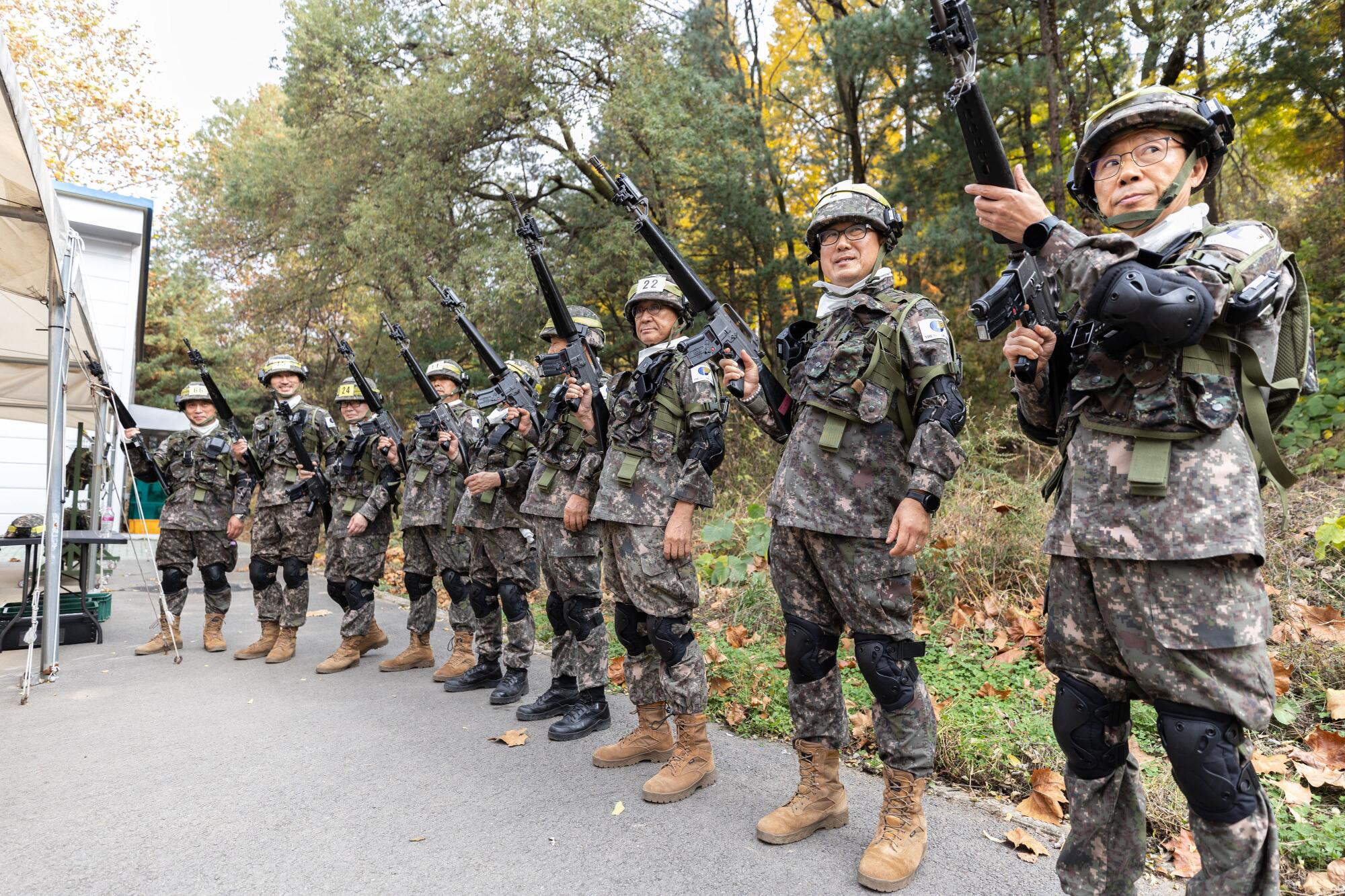 Members of the Senior Army line up with guns during military training