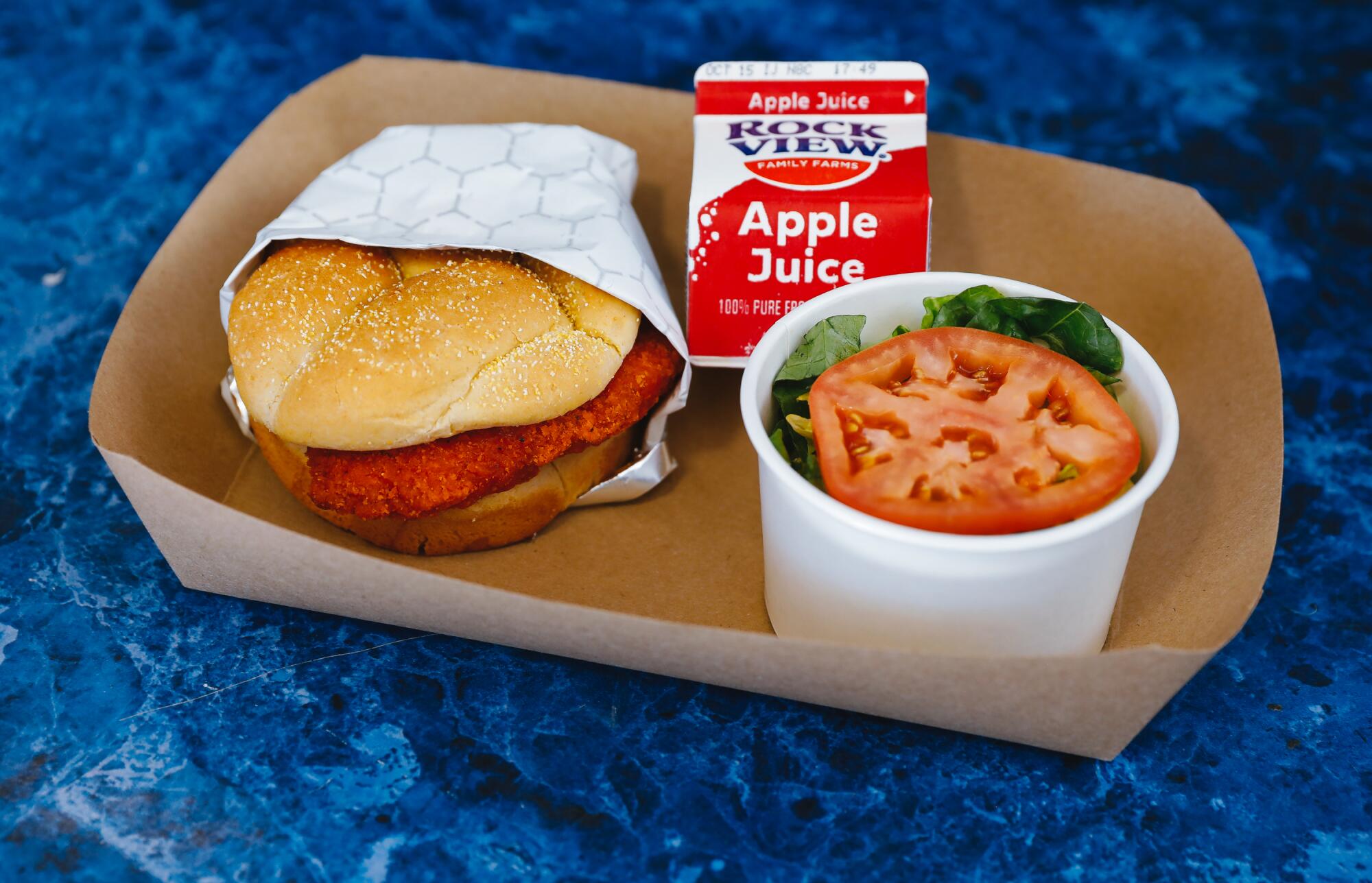 A chicken sandwich, side salad and box of juice.