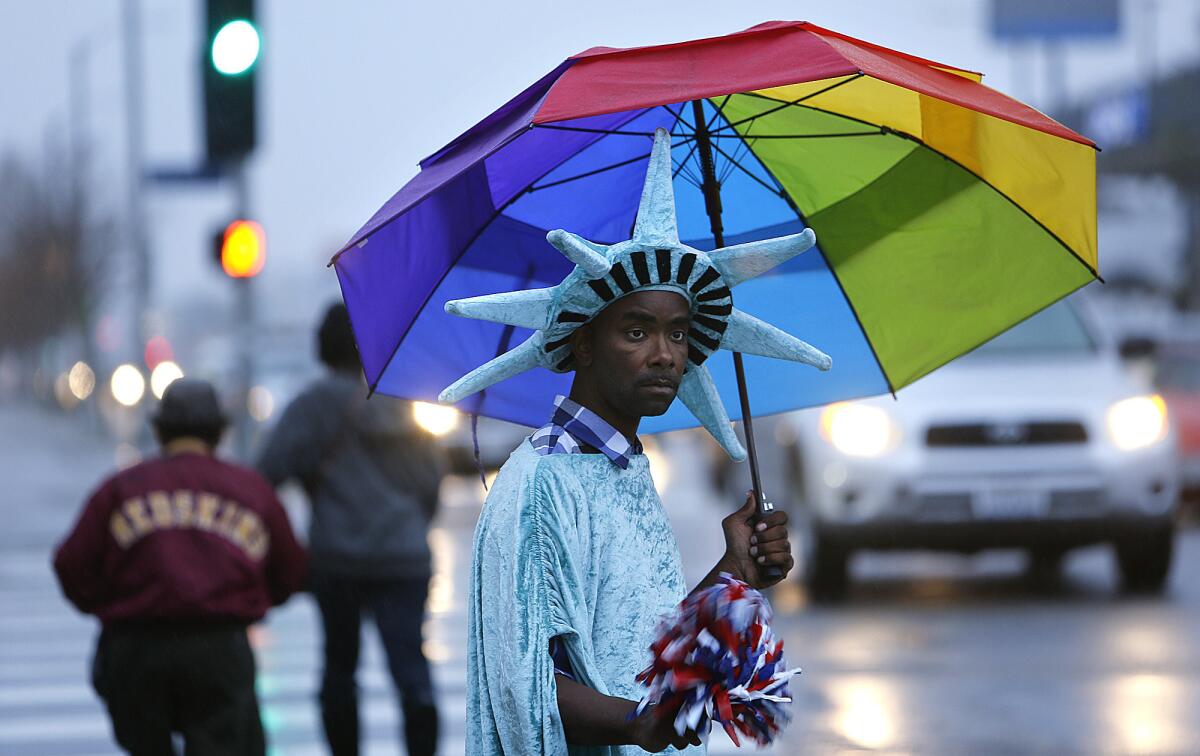 Wayne Elzy, 37, dressed up as the Statue of Liberty, keeps dry while trying to draw people's attention to a nearby tax office in South Los Angeles.