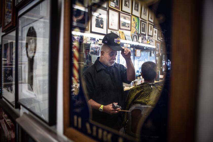 SOUTH LOS ANGELES CA JANUARY 27, 2020 -- Lawrance Tolliver, owner of Tolliver's Barber Shop in South LA, works on Jospeh Kenery Monday, January 27, 2020, where the talk was all about the helicopter crash that tooth life of Kobe Bryant, his daughter, Gianna, and seven others. (Jason Armond / Los Angeles Times)