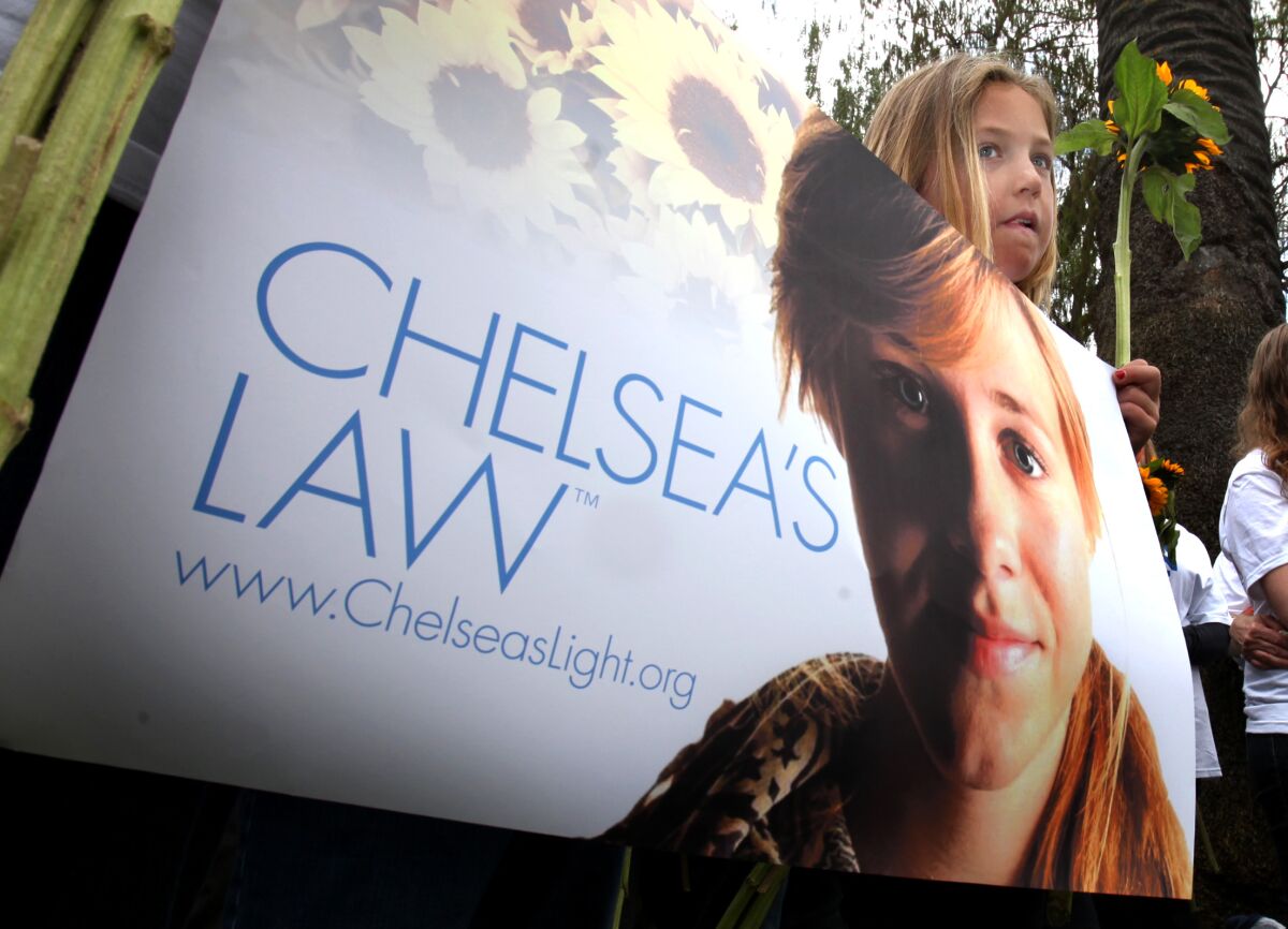 Lexi Illes, 9, of Poway, holds a sign calling for passage of a proposed measure called Chelsea's Law