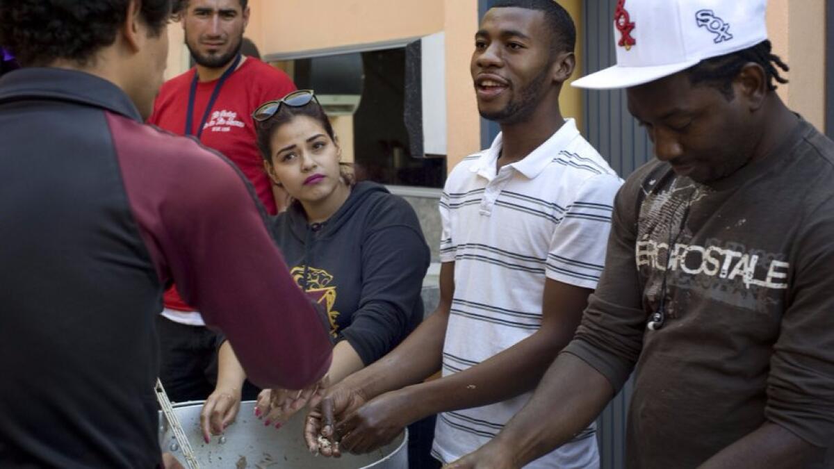 Miclisse Noel, 28, second from right, a migrant from Haiti, chats with volunteers at the Desayunador Salesiano Padre Chava shelter in Tijuana on June 8.