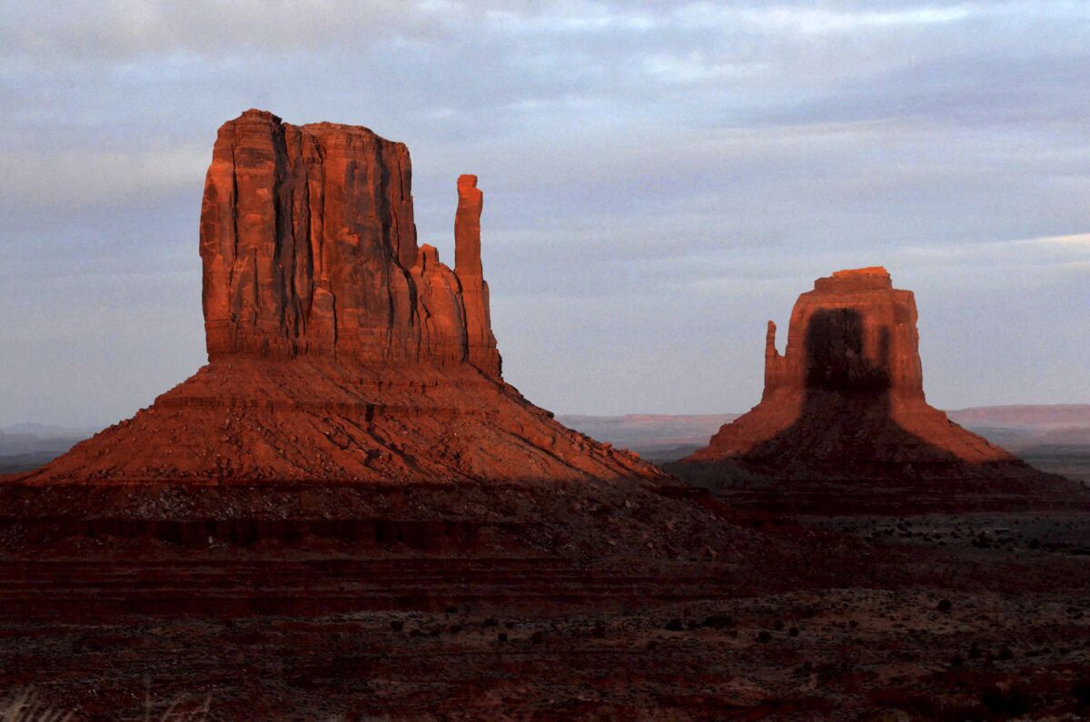 A sunset spectacle featuring two mitten-shaped rock formations crosses Monument Valley Tribal Park from the Visitors Center in Oljato-Monument Valley, Az. on Wednesday, March 29, 2023. The sunset spectacle featuring two mitten-shaped rock formations played out this week at Monument Valley on the Navajo Nation, bordering Arizona and Utah. Twice a year, in late March and mid-September, spectators, photographers and videographers get a visual treat. As the sun sinks, the West Mitten Butte's shadow crawls across the desert valley floor before climbing up the side of the East Mitten Butte. (AP Photo/Vyto Stairnksas)