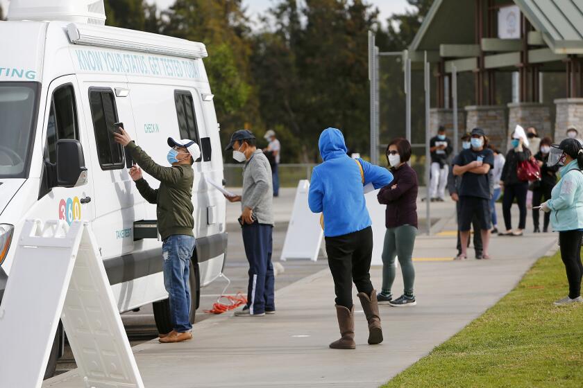 Dozens of patients wait in line to check-in at a Clinic 360 COVID-19 mobile testing site at Fountain Valley Sports Park on Tuesday morning.