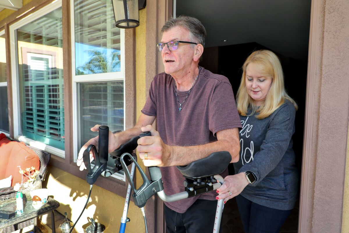 Navy veteran Bruce Courtney, who has ALS, gets assistance using his walker from his wife Lori, who teaches fourth grade. 