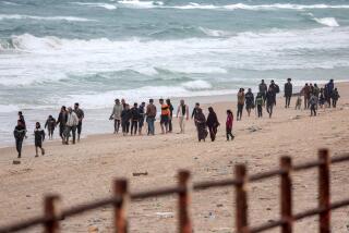 Palestinians fleeing from the area walk along the seashore as they arrive at the Nuseirat refugee camp.