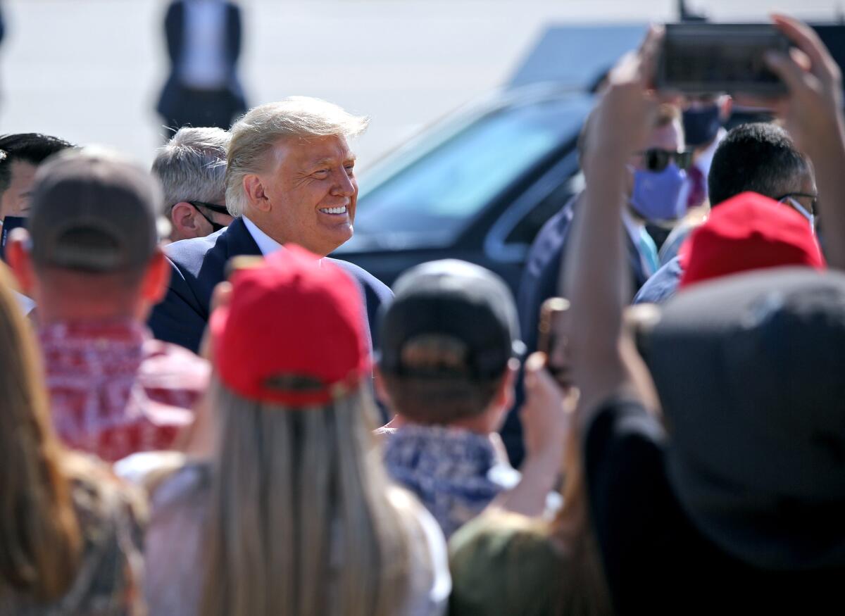 President Donald Trump greets supporters waiting for him on the tarmac at John Wayne Airport.