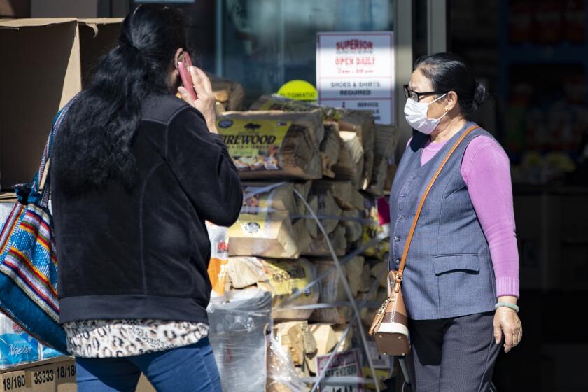 EL MONTE, CA - FEBRUARY 6, 2020: An Asian shopper exits El Superior Market wearing a protective masks while a Latino shopper enters without a mask on February 6, 2020 in El Monte, California. Many members of the Asian community are wearing protective masks to prevent coronavirus and members of the Latino community are not. (Gina Ferazzi/Los AngelesTimes)