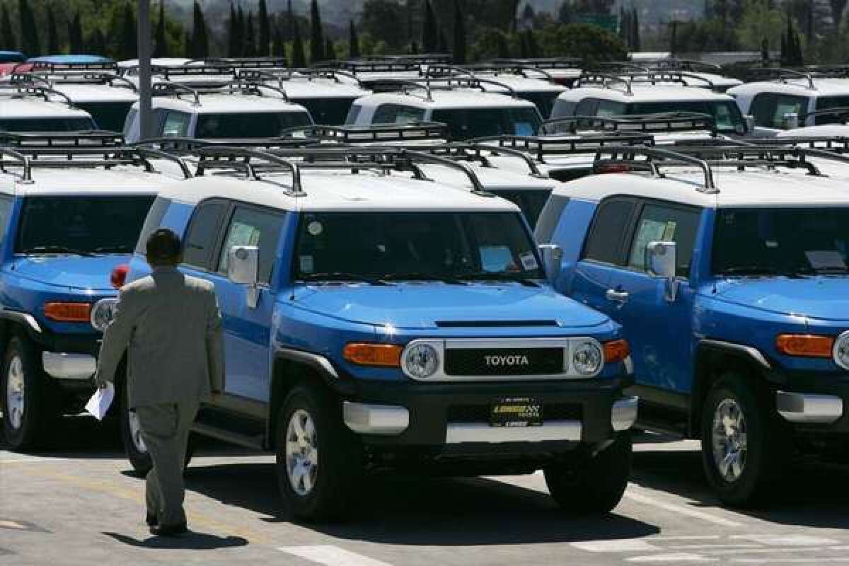 A salesman walks past rows of Toyota FJ Cruiser SUVs at a dealership in California. Toyota is issuing another recall of the vehicles, this time for 11,489 that have a headlamp problem that could blind oncoming drivers.