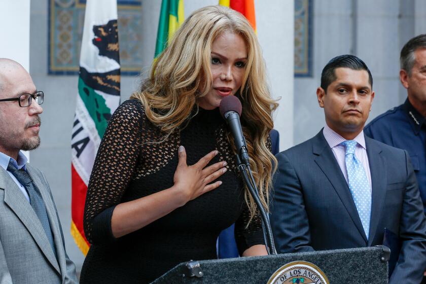 Transgender activist Maria Roman, with her fiance, Jason Taylorson, left, addresses the media during an Equality California press conference at Los Angeles City Hall on Friday.