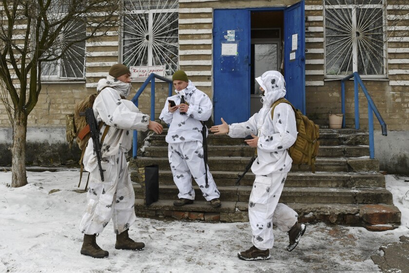 FILE - Ukrainian servicemen greet each other as they patrol a street in Verkhnotoretske village in Yasynuvata district, Donetsk region, eastern Ukraine, Jan. 22, 2022. Ukrainians in the country's east are likely to be on the front lines of war if it comes, but they are far from the people making decisions about their fate. (AP Photo/Andriy Andriyenko, File)