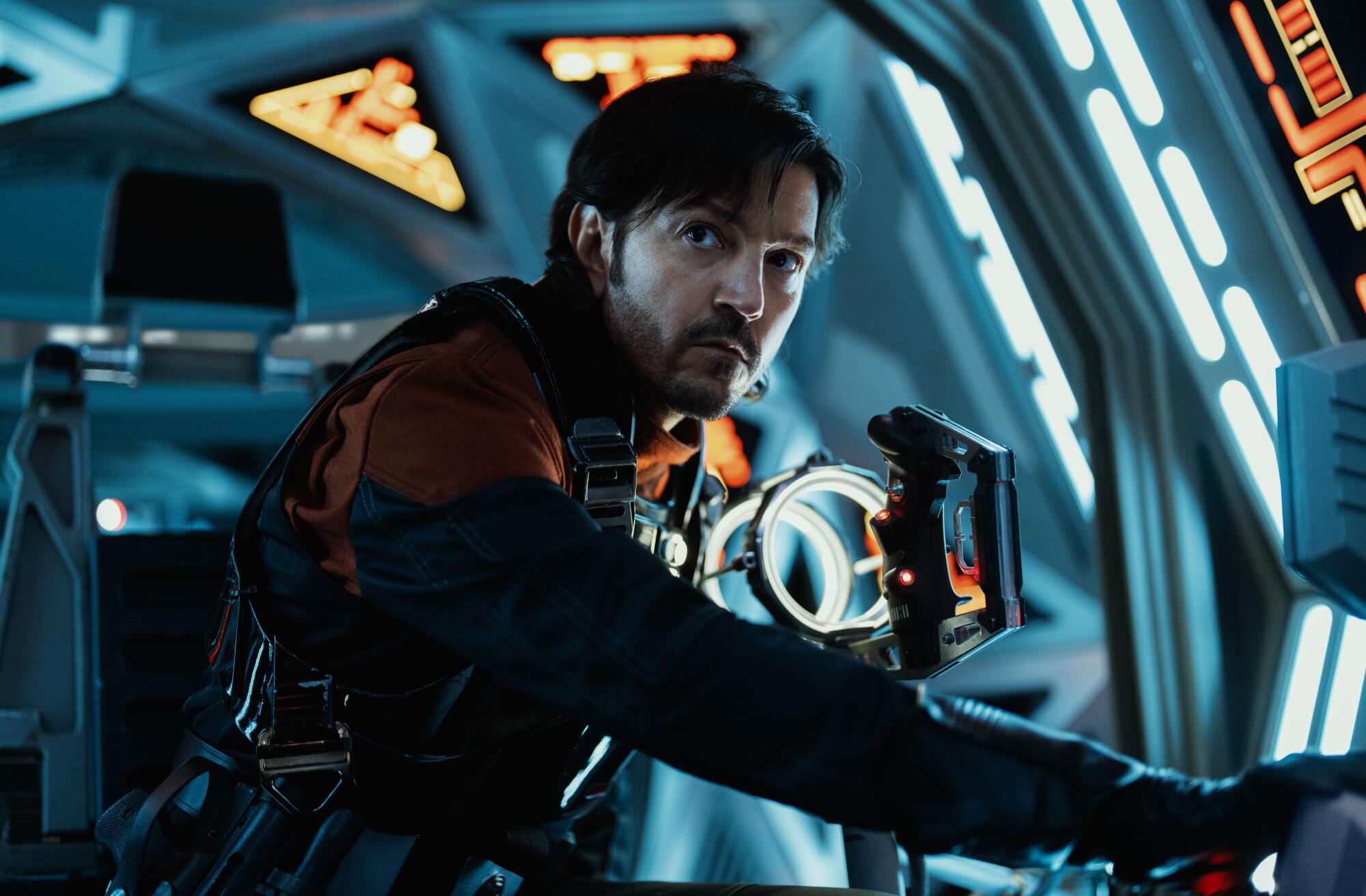 Diego Luna in a uniform looks upward in a spaceship.