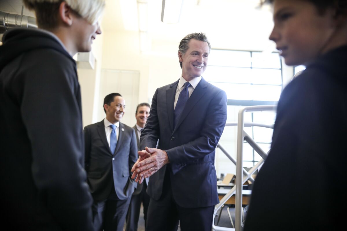 Gov. Gavin Newsom speaks with students Gavin Barry and Ryan Leitz after taking a tour of Dana Middle School in Point Loma.